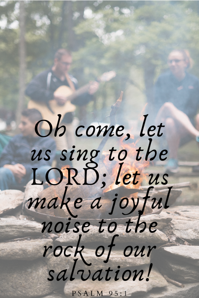 verse quote over blurred group of people singing around an outdoor fire