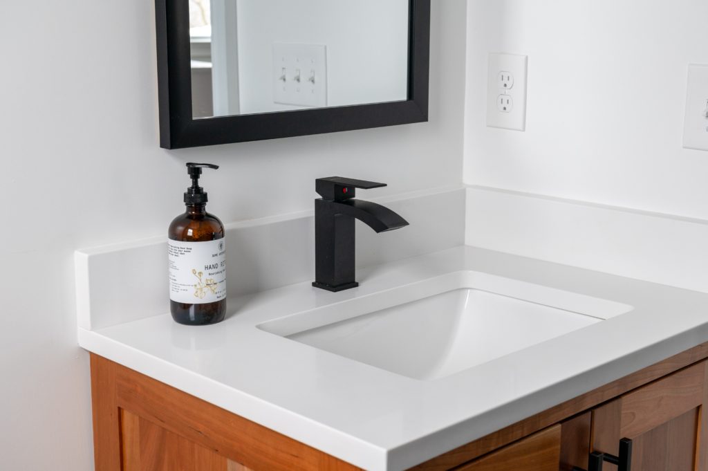 minimal modern bathroom sink with single soap bottle and a black mirror