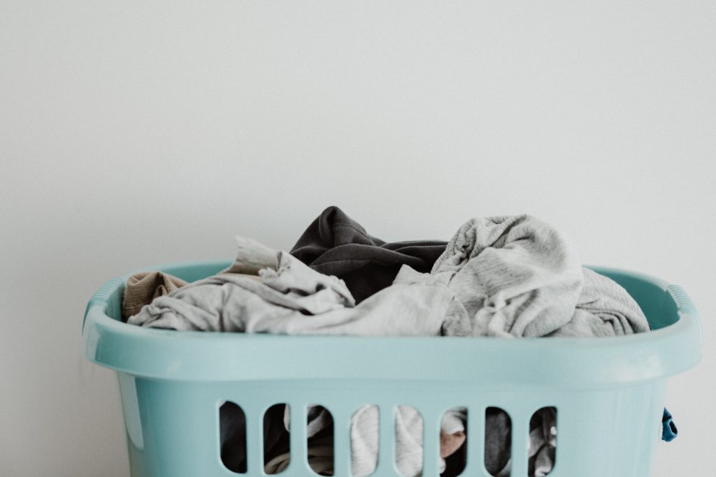 blue laundry basket filled with clothes