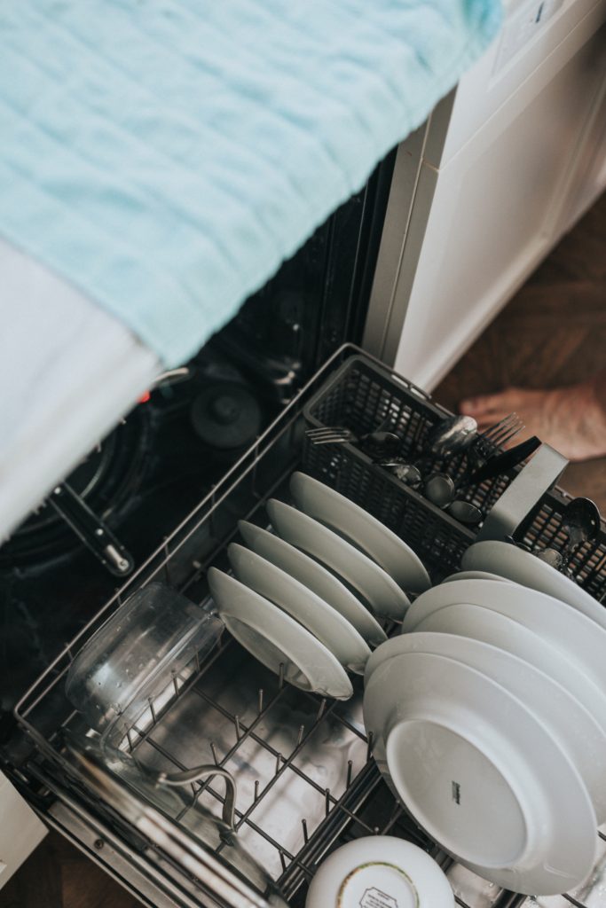 close up of dishwasher full of white dishes and silverware