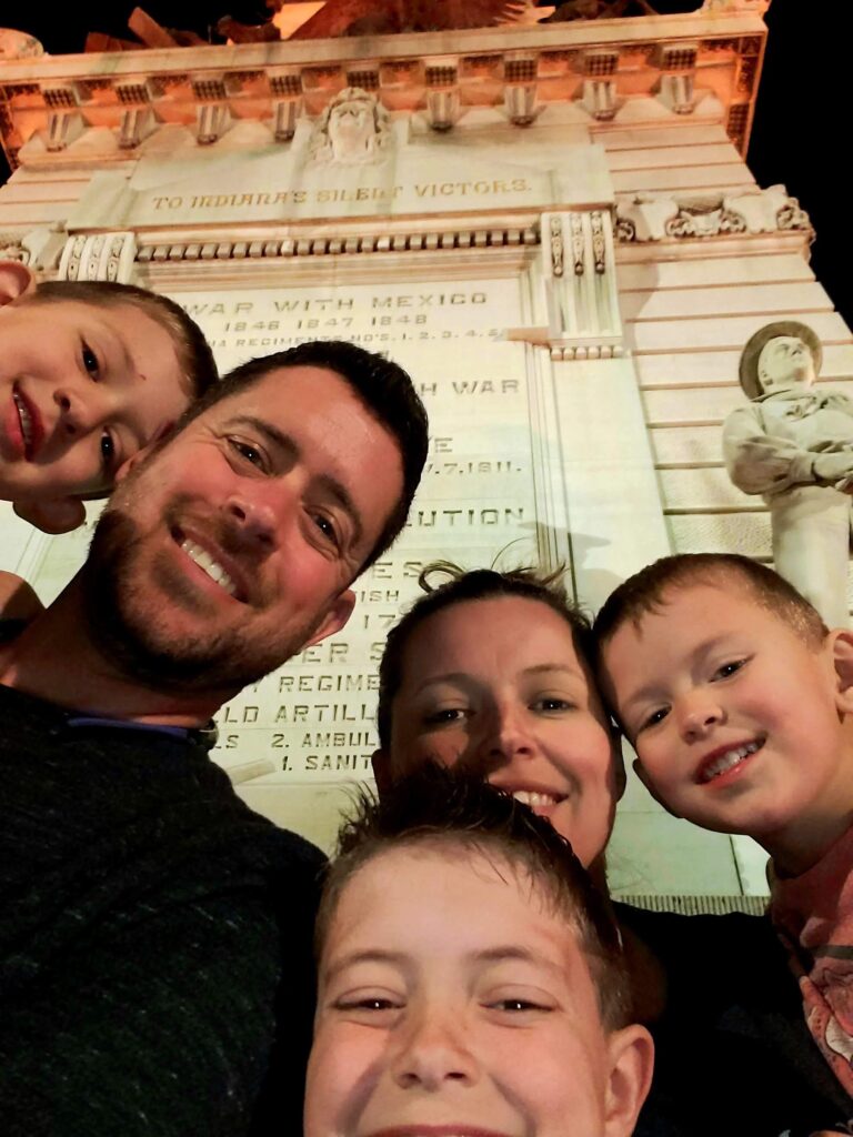 young family selfie in front of a downtown monument