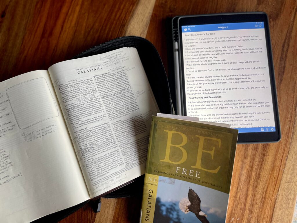 flat lay of bible, ipad, and commentary book