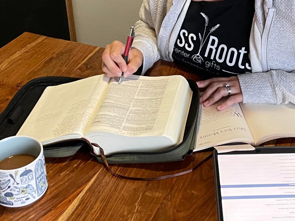 up close of woman reading her bible and studying from a commentary with a cup of coffee