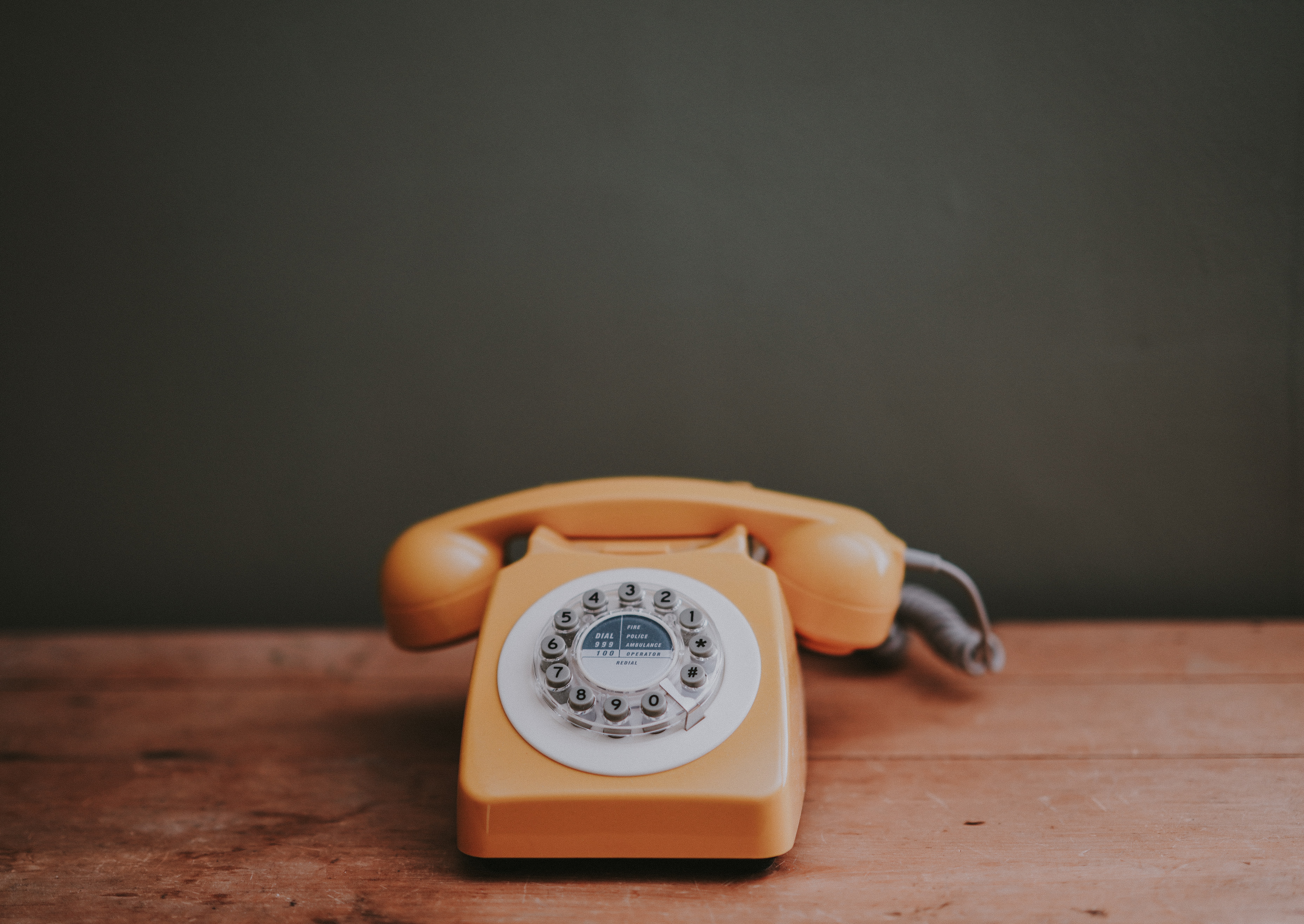 orange rotary phone on a wood table