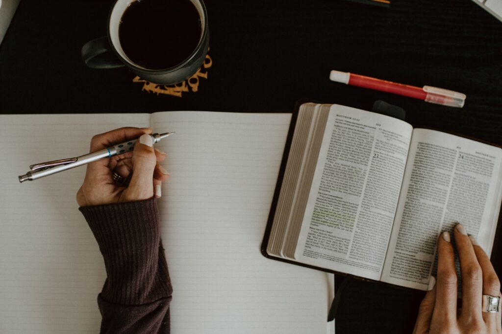 woman's hands with bible and writing in a journal