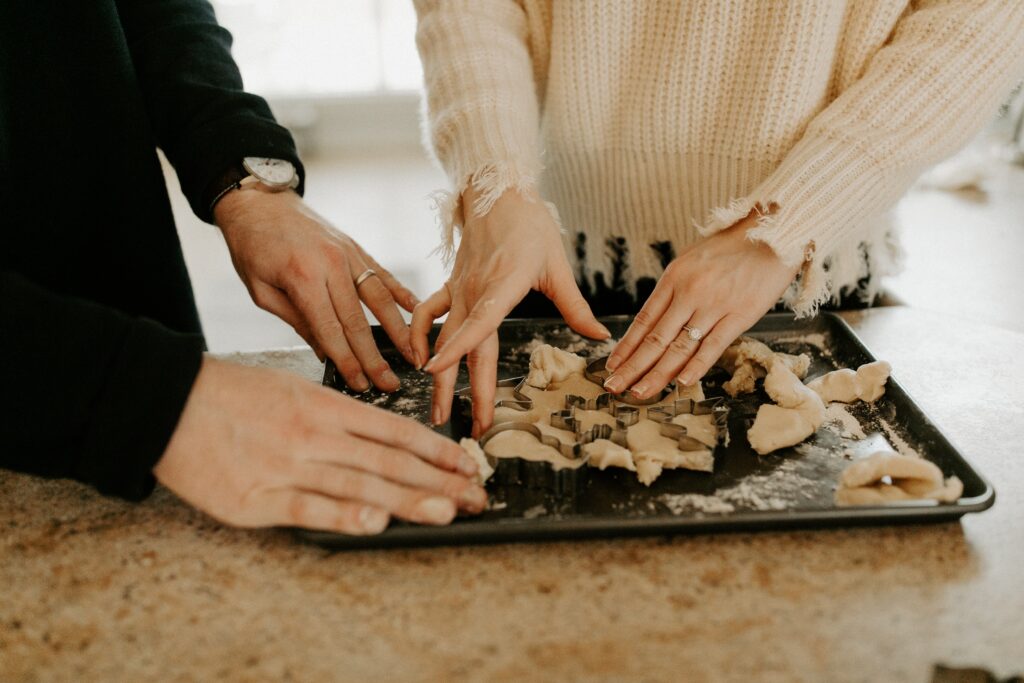 up close of two women cutting cookies on a sheet pan 