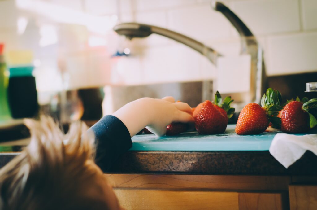 little hands reaching up on the counter to steal strawberries