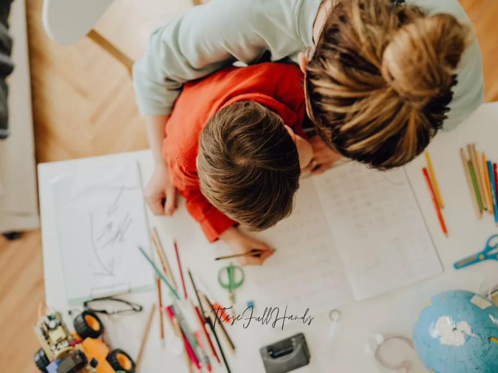 overhead of mom and son working at a table with pencils and notebooks spread out