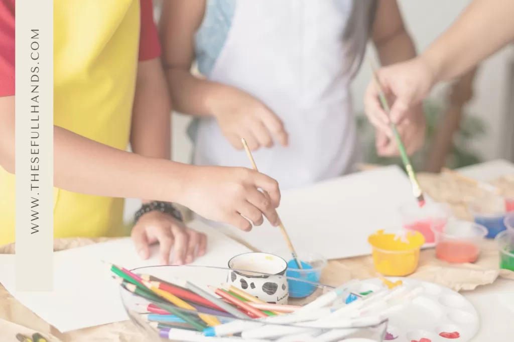 up close of kids painting on paper with extra colored pencils