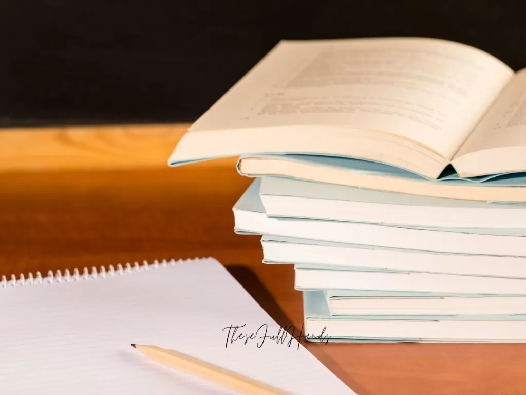 stack of notebooks with one opened and a sharpened pencil on top of another notebook