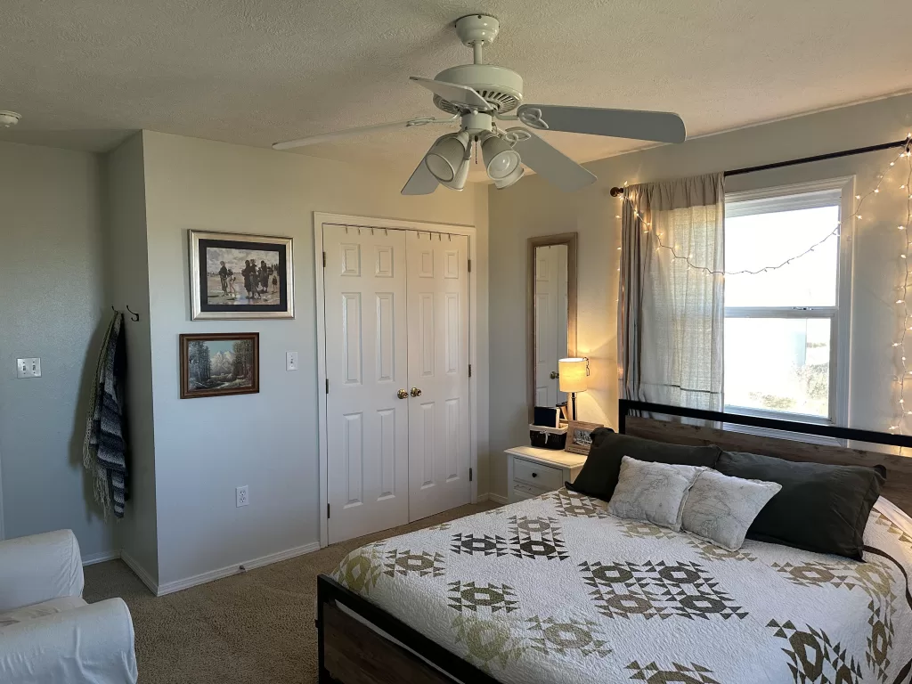 a light blue bedroom with art on the walls and a quilt on the bed