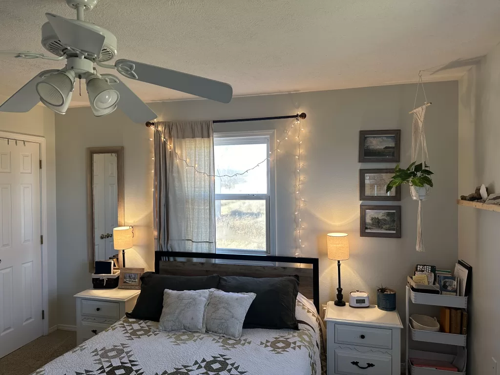 bed in front of a window with twinkle lights over the window covering