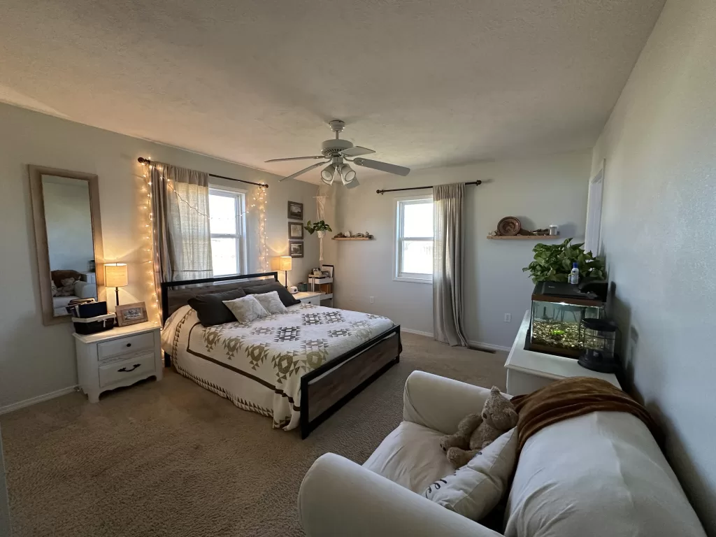 full view of a master bedroom with two windows and a fish tank