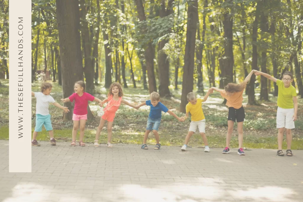 seven kids playing outside on pavement in a chain of hands