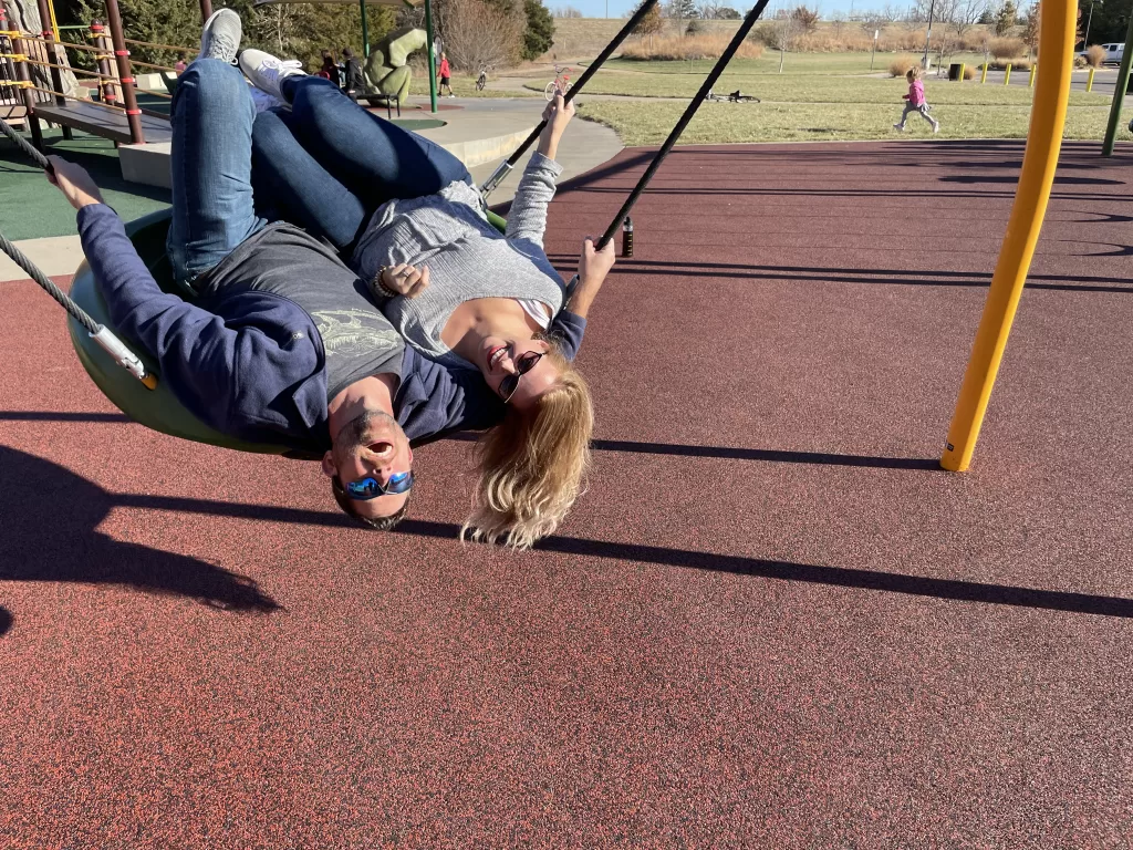 man and wife laughing upside down in a big disc swing