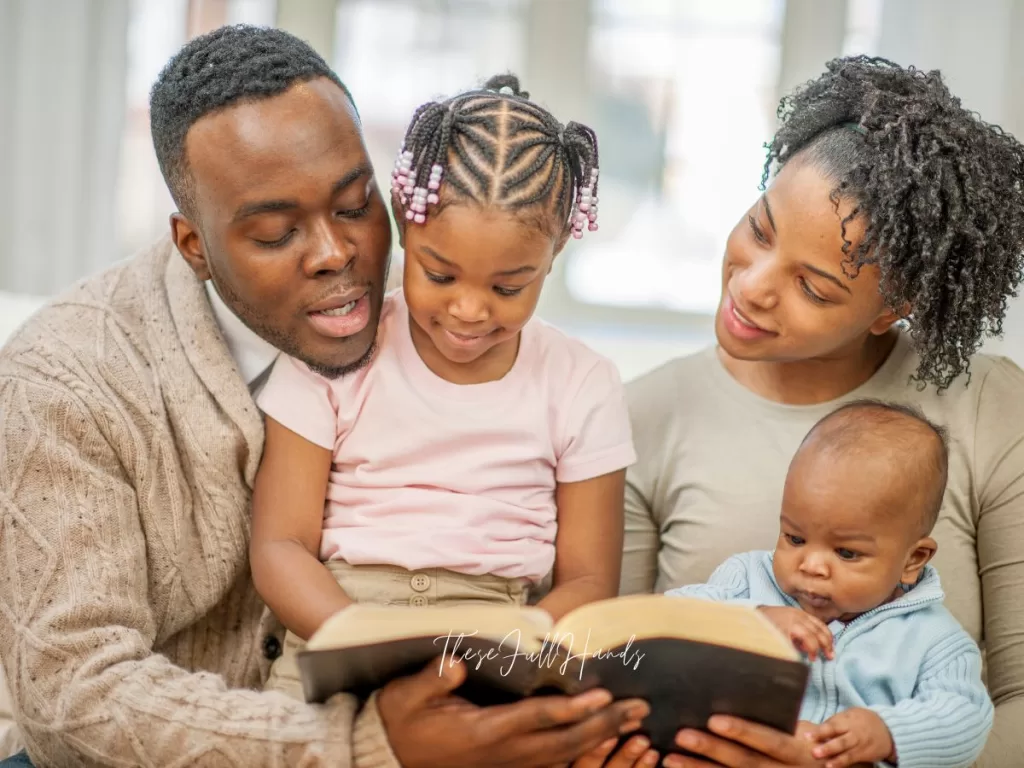 husband, wife, two small kids reading the bible together and teaching the Bible to their kids