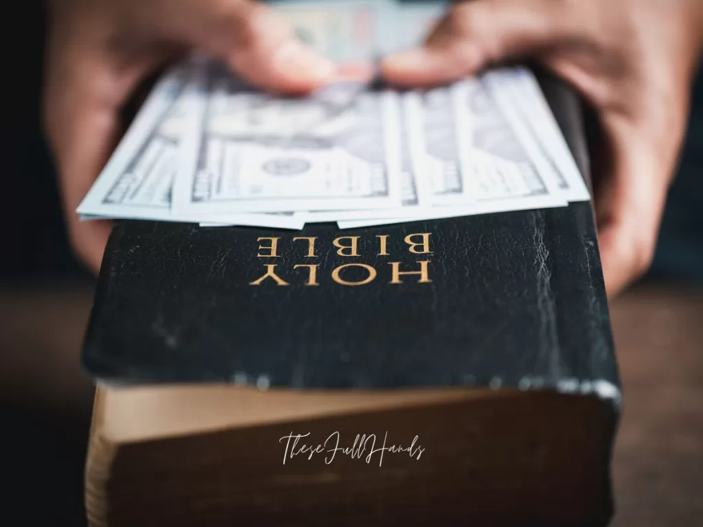 hands holding cash laid over a Bible