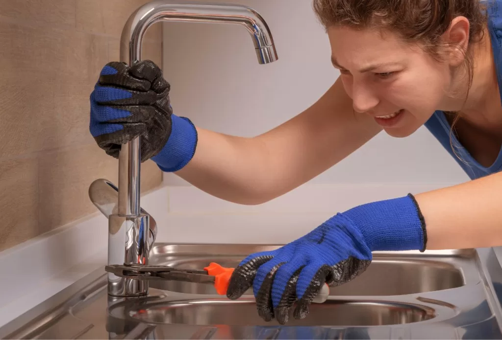 woman saving money by repairing the kitchen sink herself