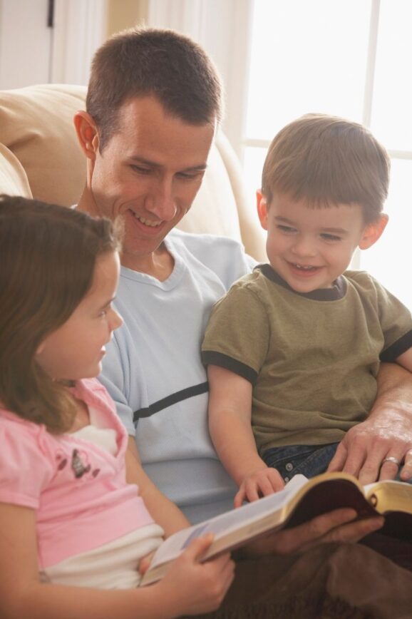 father and kids reading the Bible on couch