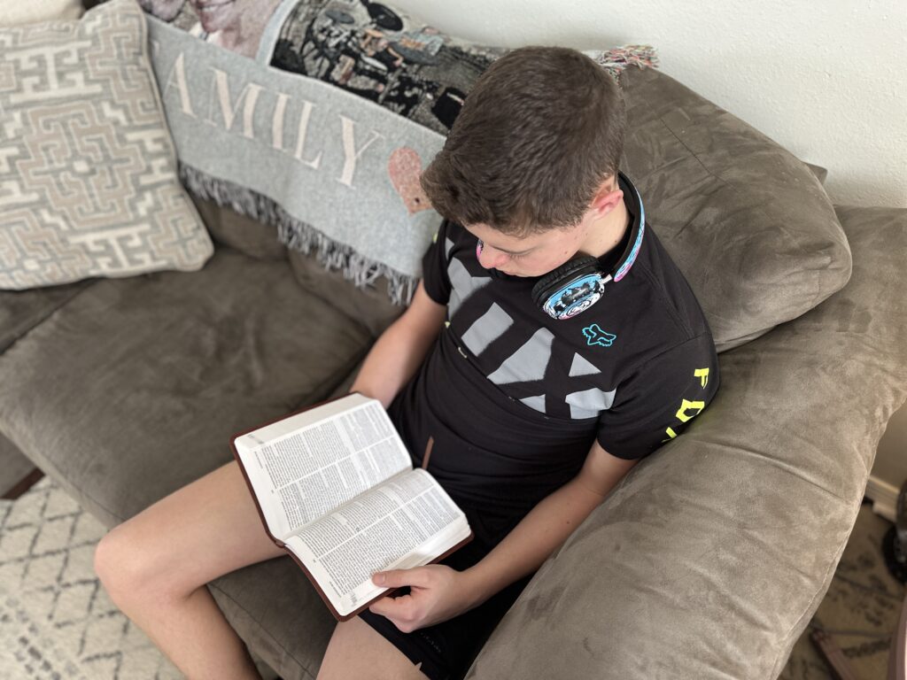 teen boy reading his bible on the couch
