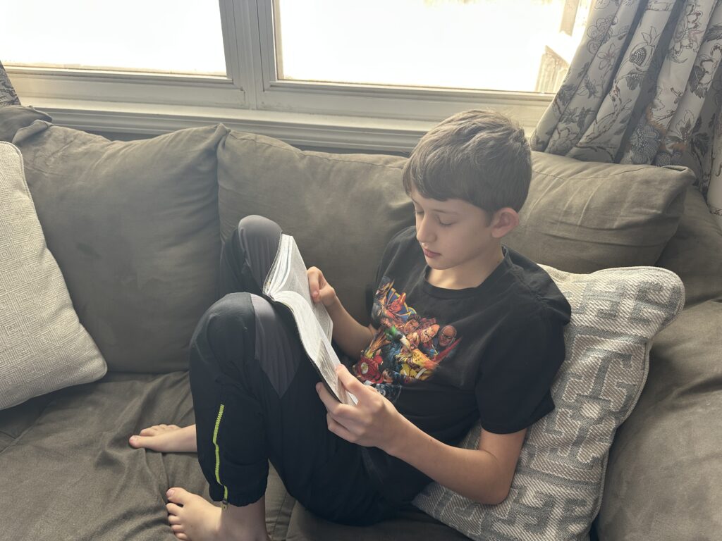 boy sitting on couch reading his bible