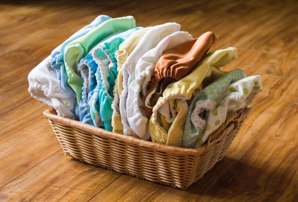 basket full of cloth diapers of various colors. cloth diapering is a money saving tip for single income families