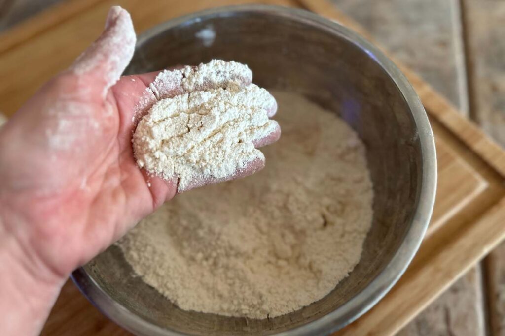 hand holding the mixed dry ingredients to show the desired texture of mixture