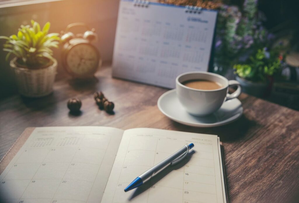 flat lay of planner, calendar, and a cop of coffee