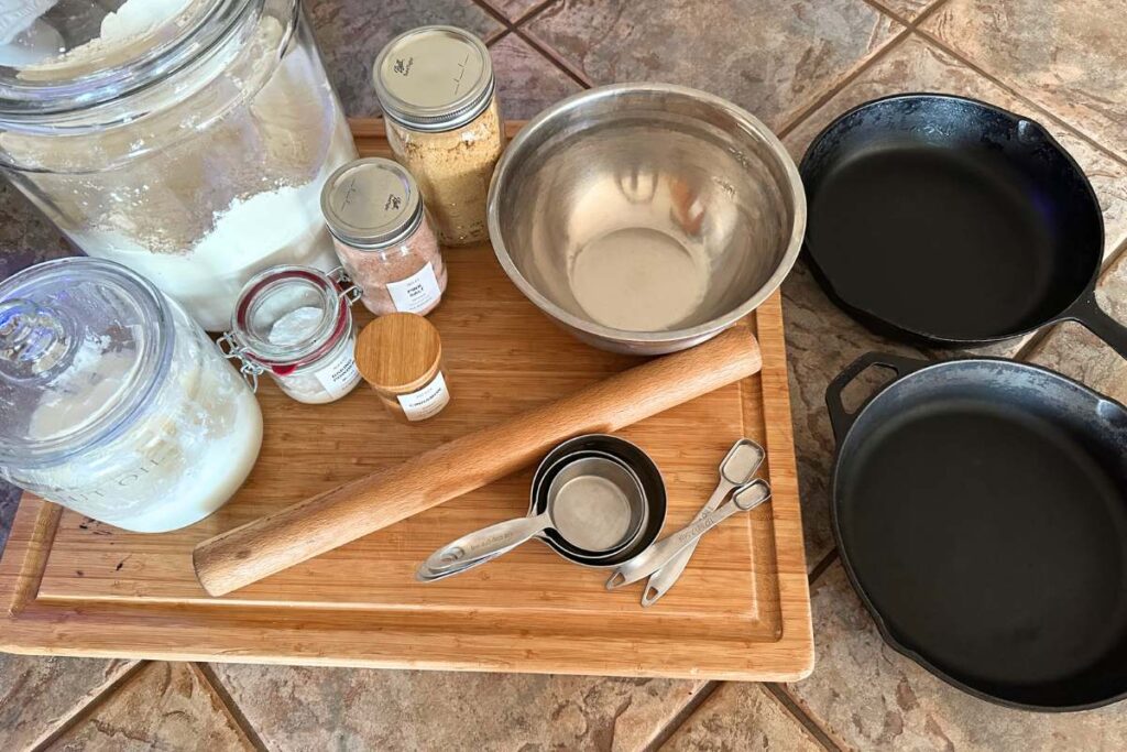 Birdseye view of ingredients, measuring utensils, and cast iron skillets for baking cinnamon rolls